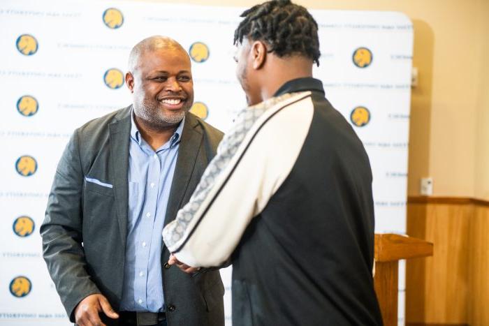 One male student shaking hands with male professor.