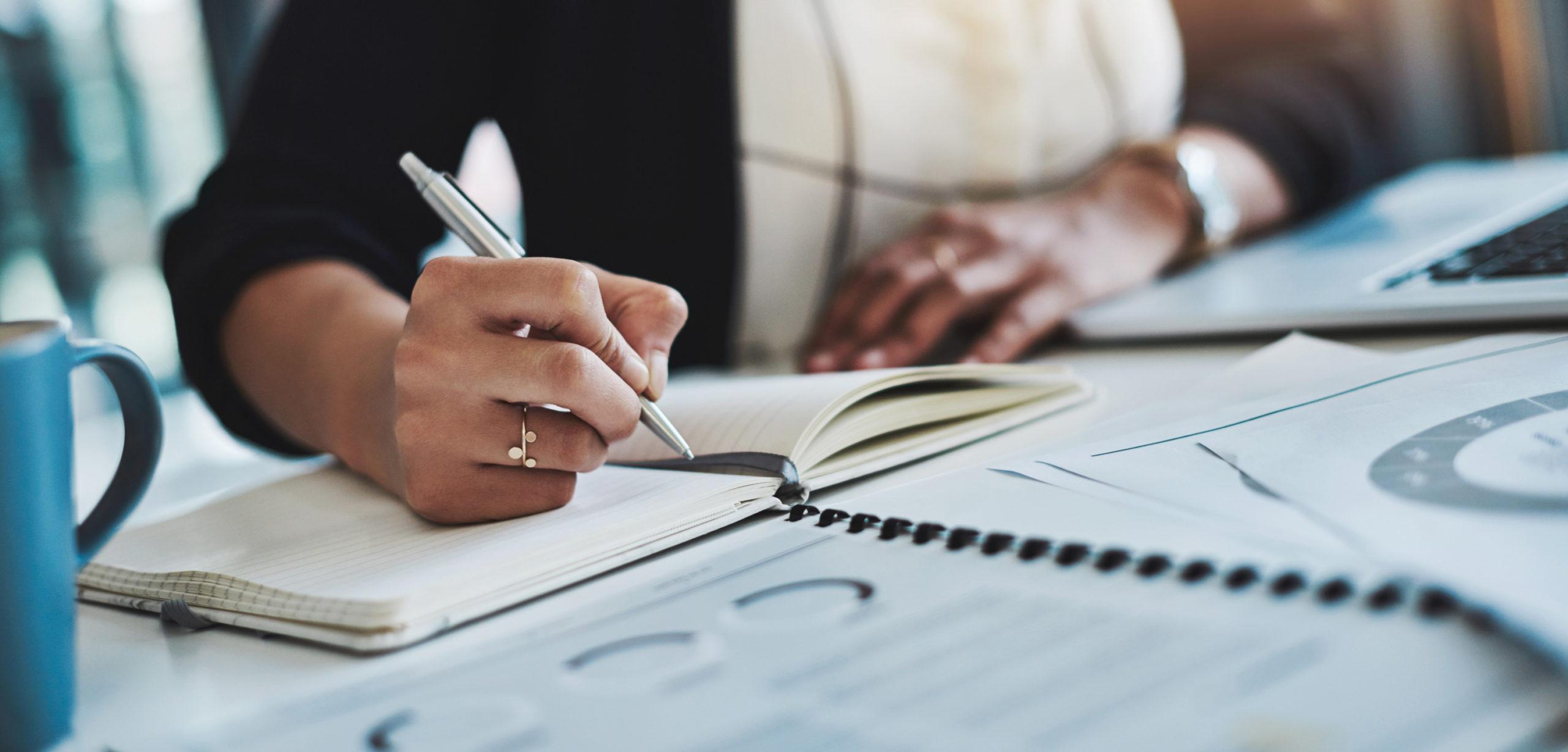 Cropped shot of a businesswoman making notes at her desk in a modern office.