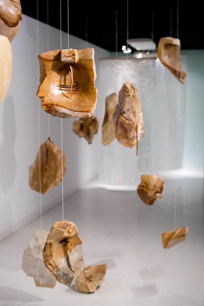 Broken pieces of pottery suspended from clear line.