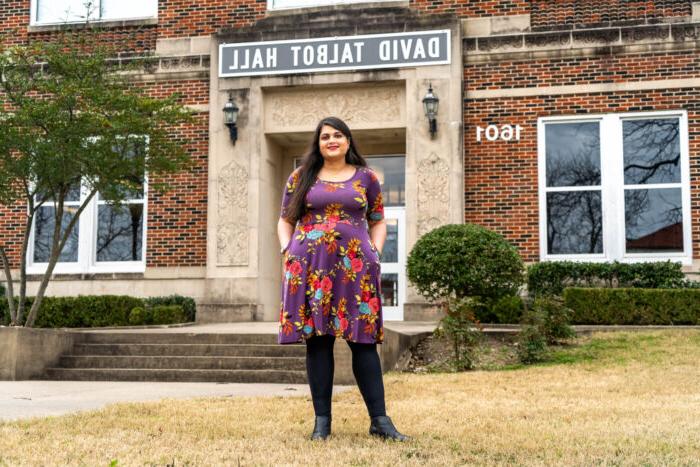 A female professor in front of a bricked building.