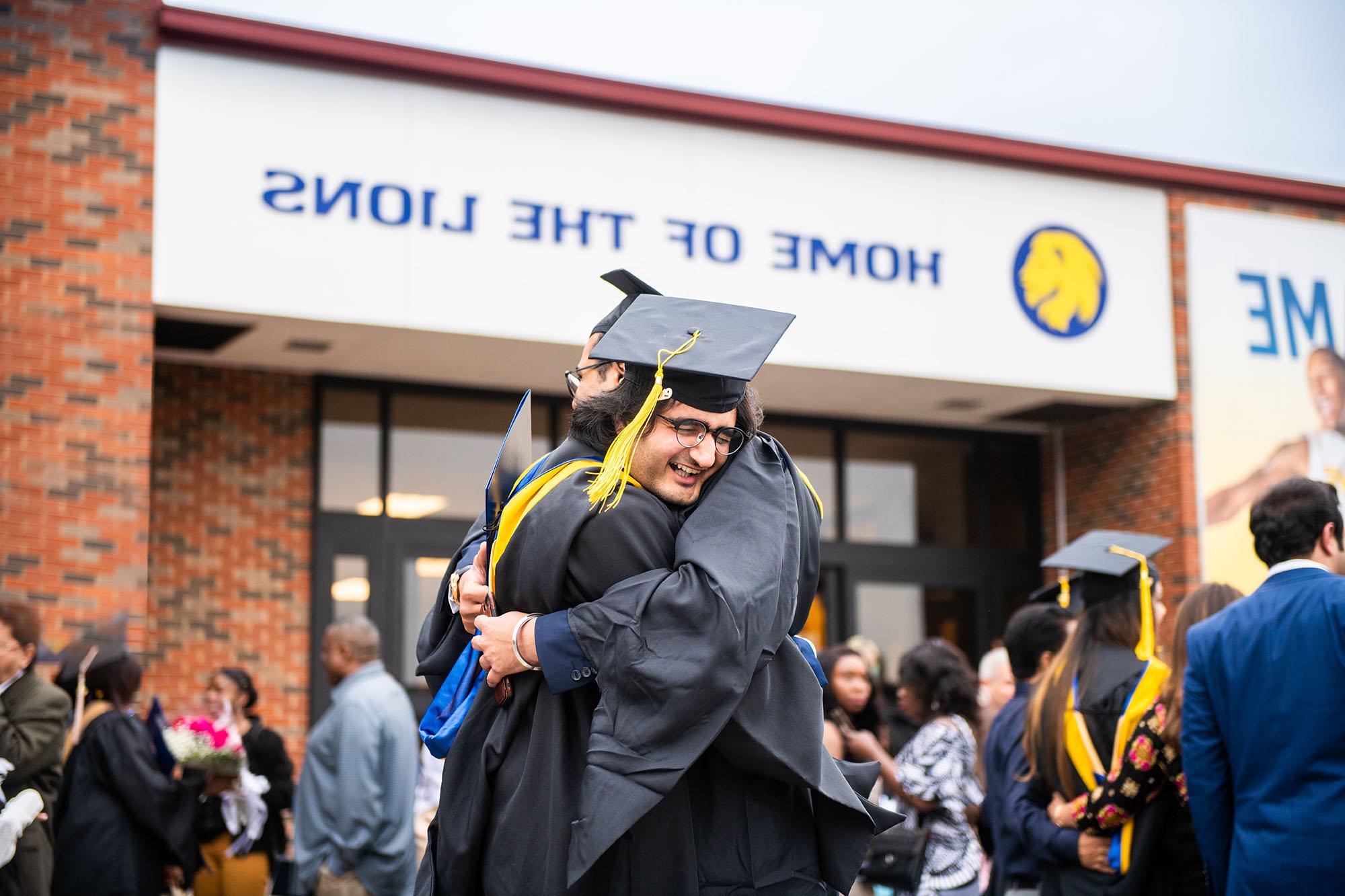 Two students hugging each other after graduation.