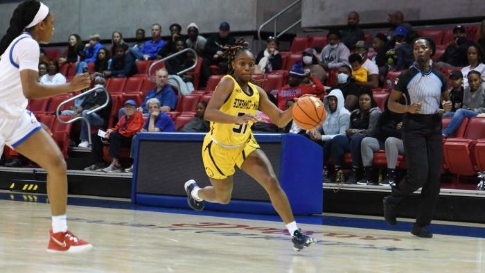 A female basketball player dribbling the ball.