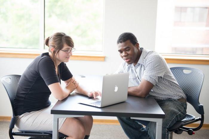 A female student showing a male student something on the computer.