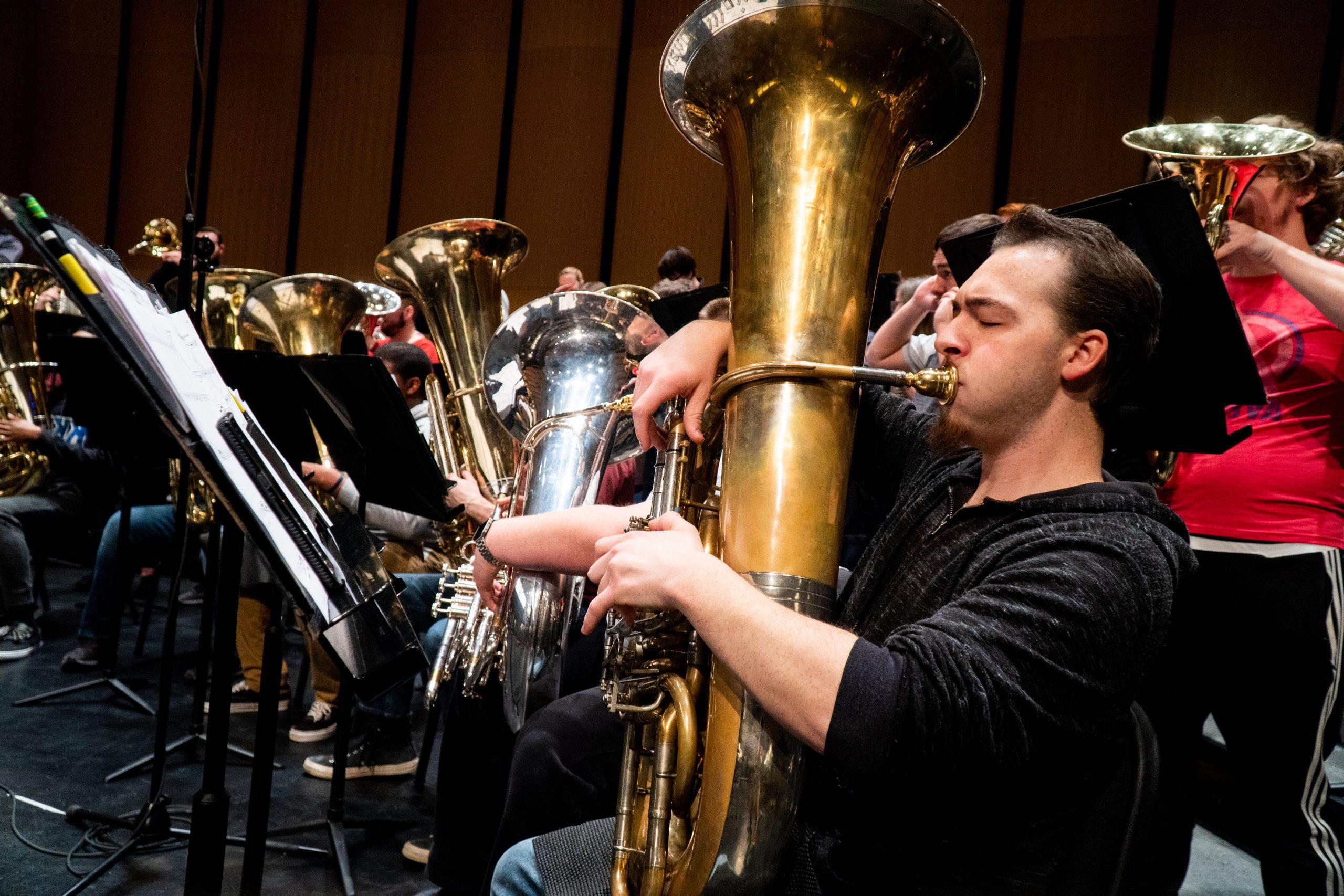 A male student playing the tuba.