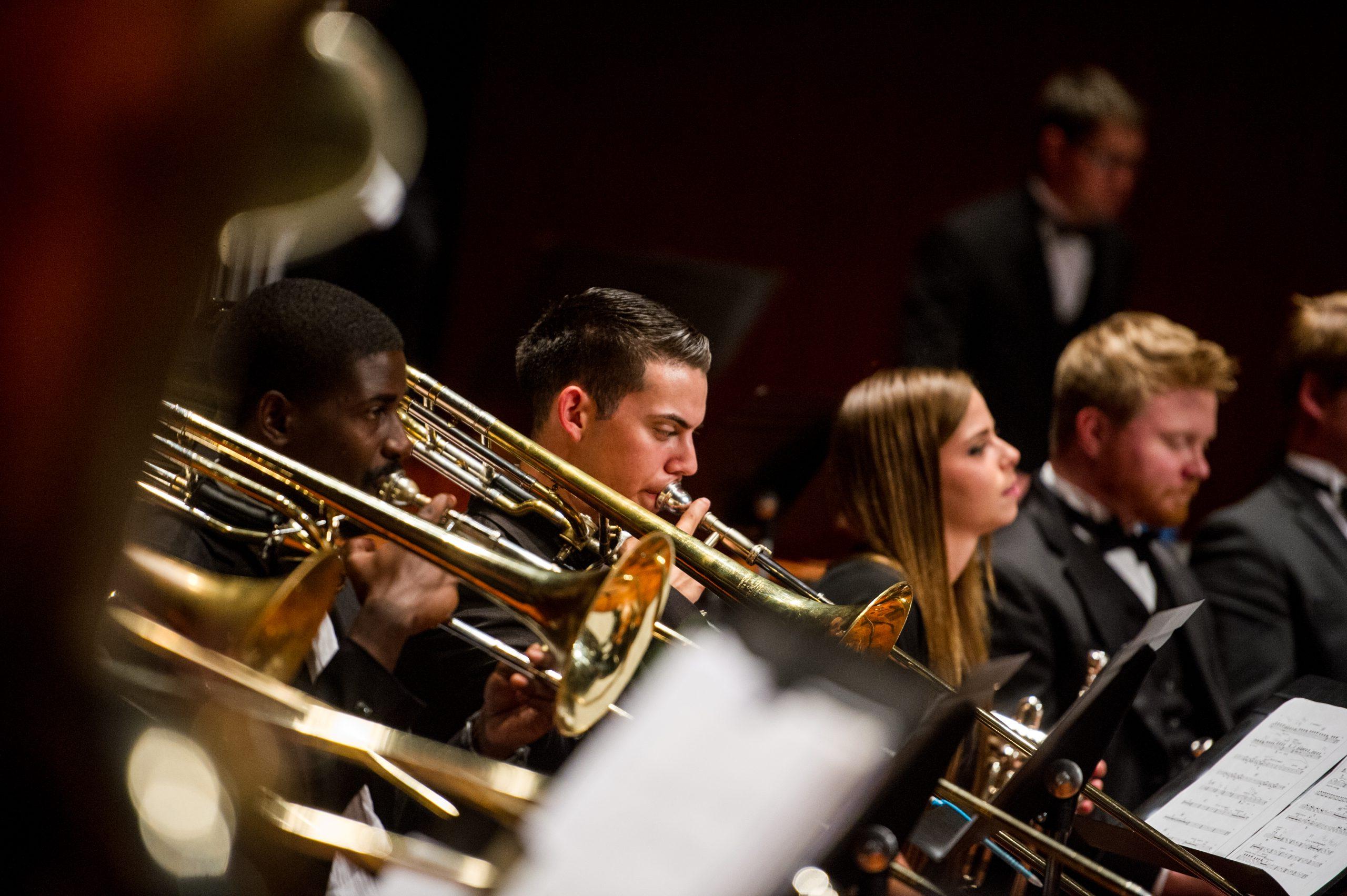 Three individual playing the trombone.