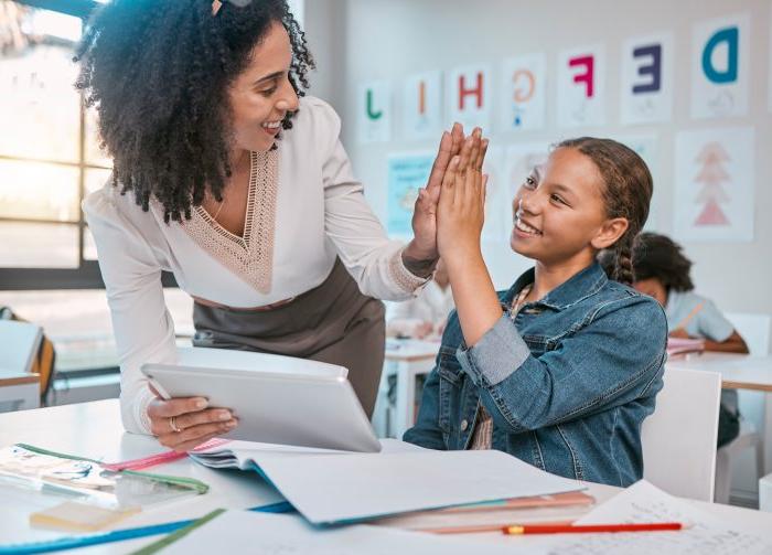 Tablet, high five and teacher with child education, learning and support, achievement and classroom goal. Mentor, black woman or person and girl in success hand sign for English, language development.