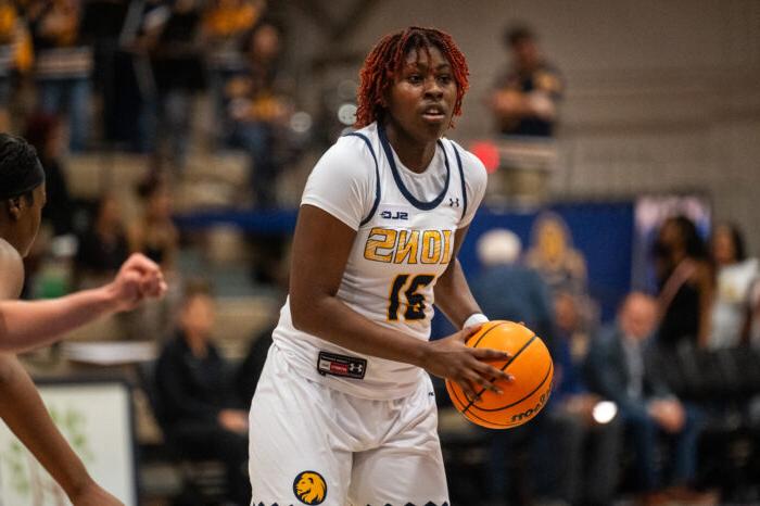 A female basketball player wearing a Texas A&M-Commerce Lions jersey, number 31, focuses while holding an orange basketball, preparing for a play during a game.